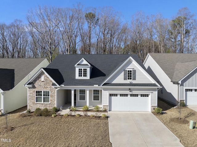 view of front of house featuring stone siding, driveway, a garage, and roof with shingles