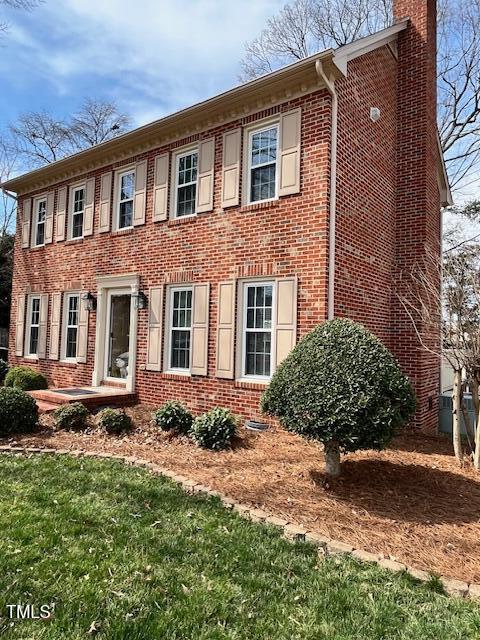 colonial home with brick siding and a chimney