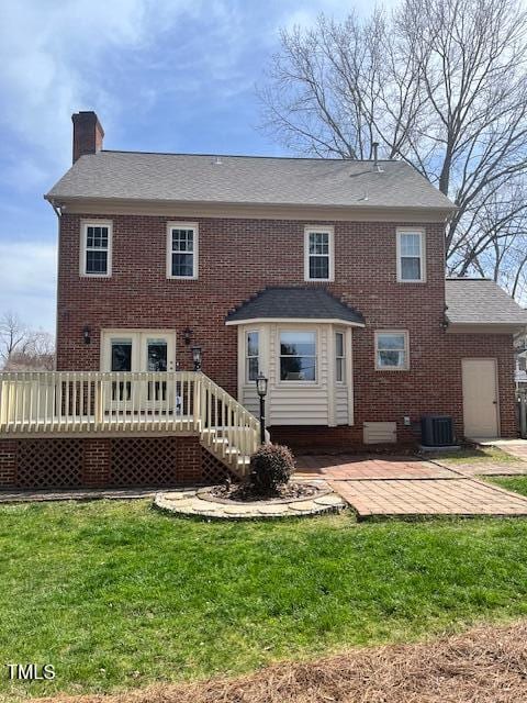 rear view of house featuring a wooden deck, brick siding, a chimney, a patio area, and a lawn