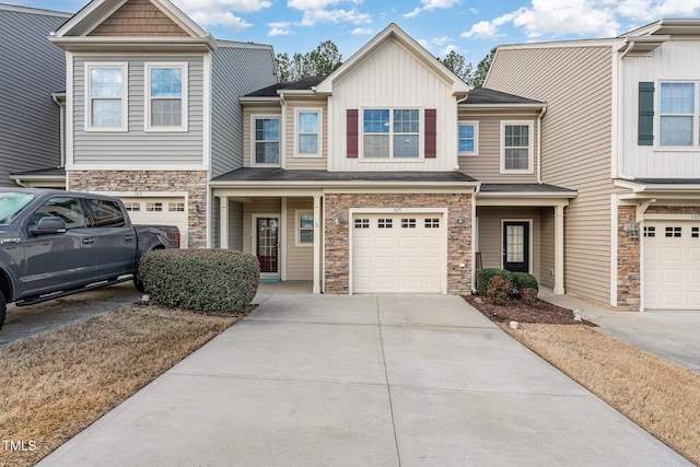 view of property featuring a garage, stone siding, board and batten siding, and driveway