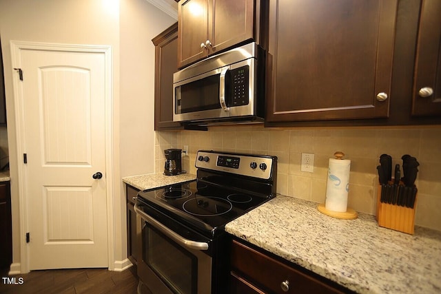 kitchen featuring tasteful backsplash, stainless steel appliances, light stone countertops, dark brown cabinets, and dark wood-style flooring