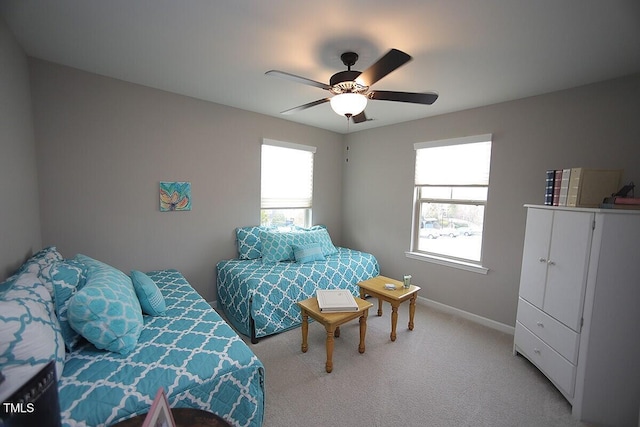 bedroom with multiple windows, light colored carpet, baseboards, and ceiling fan