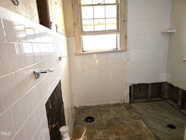 bathroom with tiled shower and tile walls