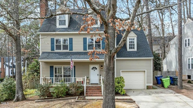 view of front facade featuring a porch, roof with shingles, a chimney, a garage, and driveway