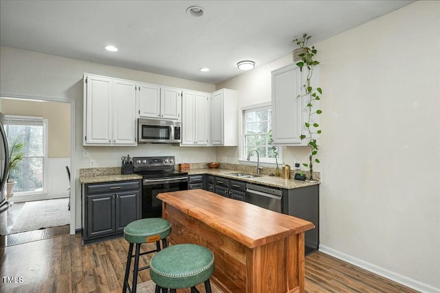 kitchen with gray cabinets, a sink, dark wood-style floors, white cabinetry, and stainless steel appliances