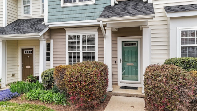 view of exterior entry with a shingled roof