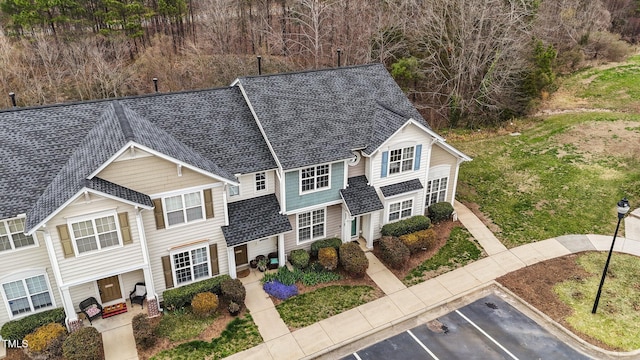 view of front facade with roof with shingles and uncovered parking