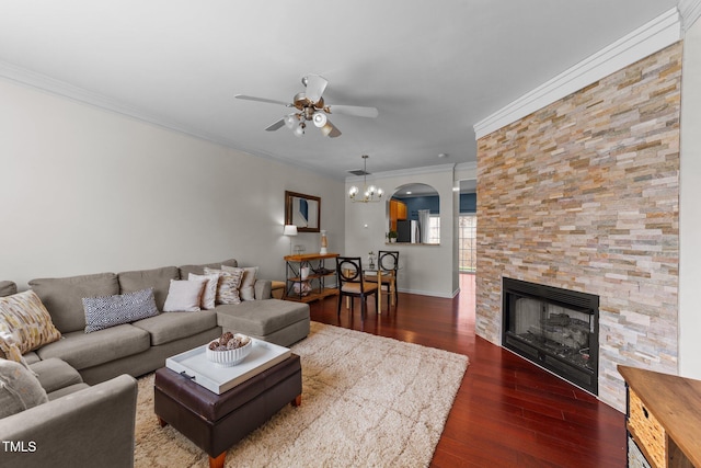 living area featuring wood finished floors, a ceiling fan, a fireplace, arched walkways, and crown molding