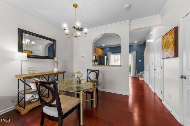 dining room featuring baseboards, a chandelier, ornamental molding, wood finished floors, and arched walkways