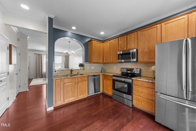 kitchen with a sink, light stone counters, stainless steel appliances, decorative backsplash, and dark wood-style flooring