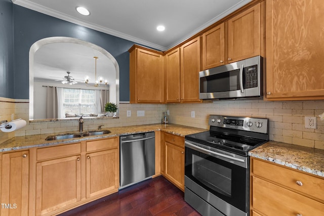 kitchen featuring dark wood-type flooring, a sink, arched walkways, appliances with stainless steel finishes, and crown molding