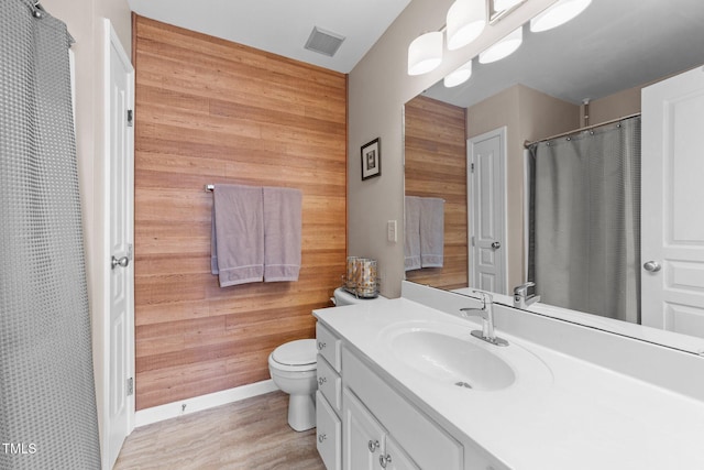 full bath featuring visible vents, toilet, wood walls, and vanity