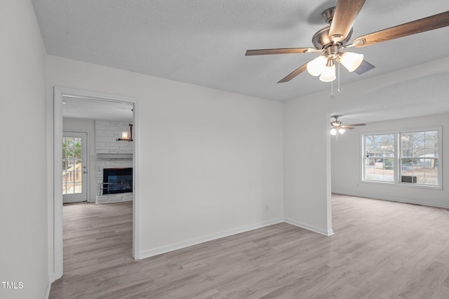 205 Woodside Dr, Goldsboro, NC 27534 - unfurnished room with baseboards, a fireplace, wood finished floors, a textured ceiling, and a ceiling fan