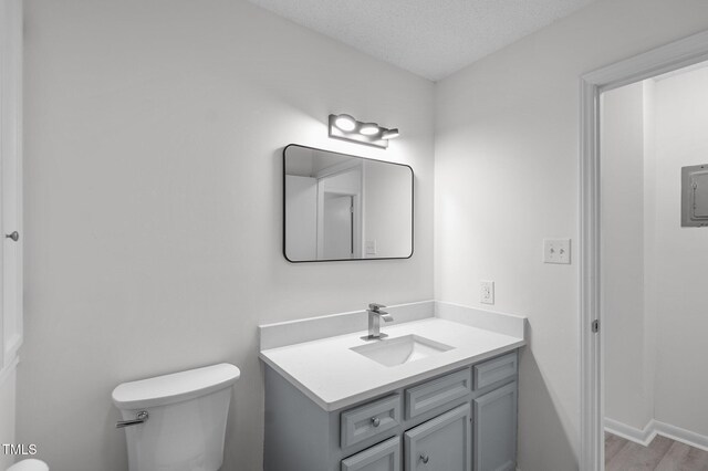 205 Woodside Dr, Goldsboro, NC 27534 - half bathroom featuring toilet, a textured ceiling, wood finished floors, baseboards, and vanity