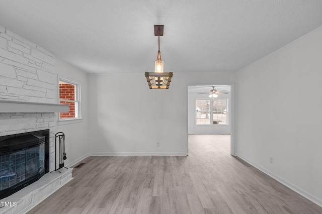205 Woodside Dr, Goldsboro, NC 27534 - unfurnished living room with wood finished floors, baseboards, visible vents, ceiling fan, and a stone fireplace