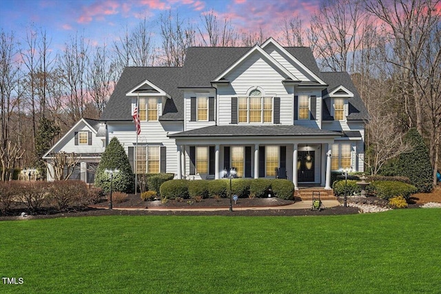 traditional-style home featuring a lawn and a shingled roof