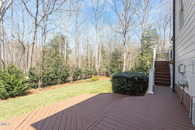 wooden deck with a wooded view, stairs, and a yard