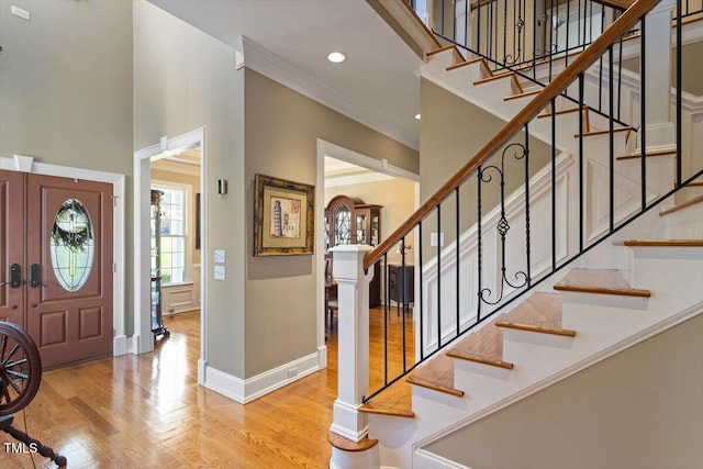 entryway featuring crown molding, wood finished floors, baseboards, and a towering ceiling