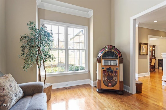 sitting room with light wood finished floors, visible vents, crown molding, and baseboards