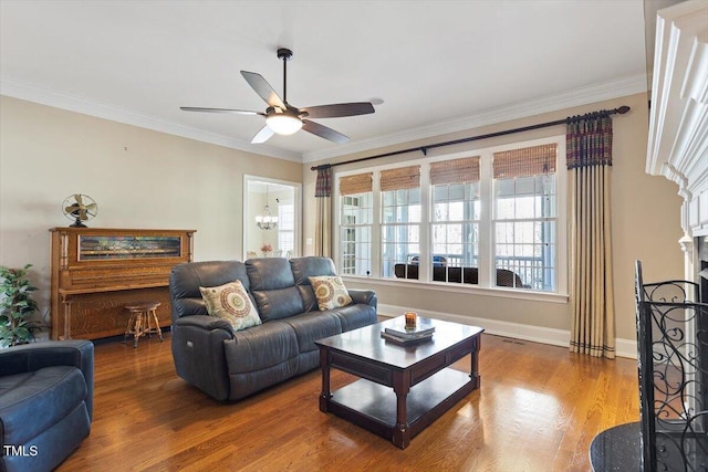 living area with ornamental molding, a fireplace, baseboards, and wood finished floors