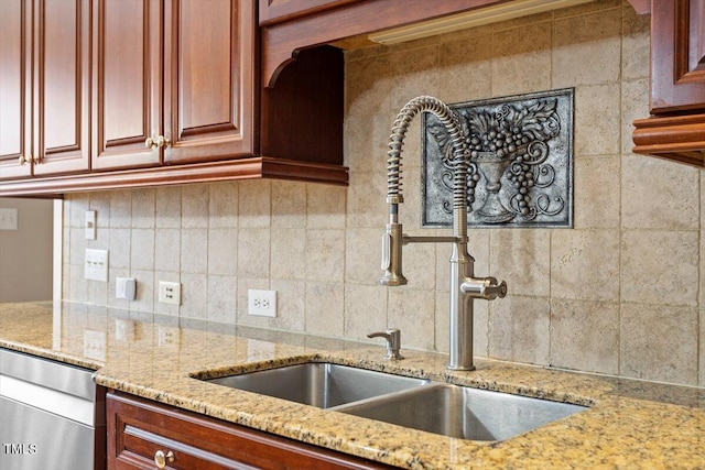 kitchen featuring tasteful backsplash, light stone counters, and a sink