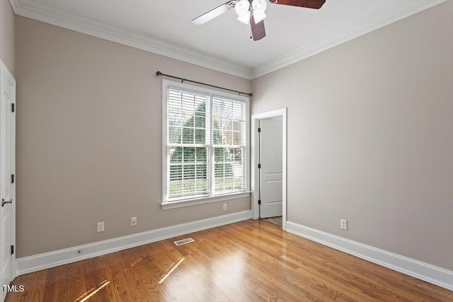 spare room with plenty of natural light, wood finished floors, visible vents, and baseboards