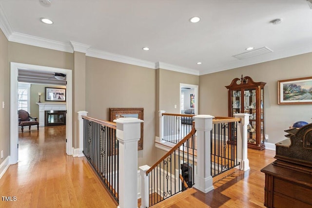 hall with an upstairs landing, visible vents, crown molding, and light wood-type flooring