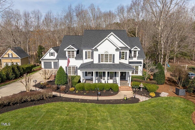 traditional-style home with a garage, a porch, a shingled roof, and a front lawn