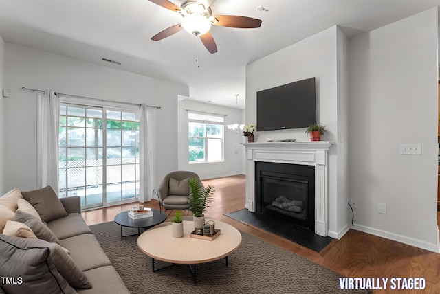 living area featuring visible vents, baseboards, a glass covered fireplace, and wood finished floors