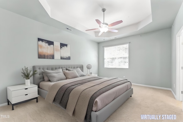 bedroom featuring a tray ceiling, baseboards, light colored carpet, and visible vents