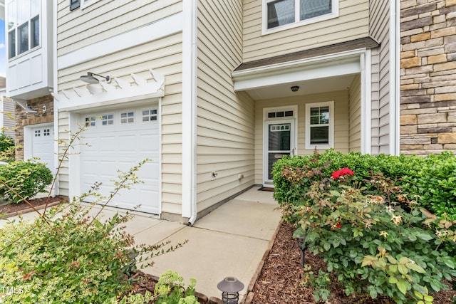 entrance to property featuring a garage and stone siding