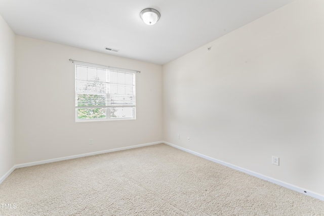 carpeted spare room with visible vents and baseboards