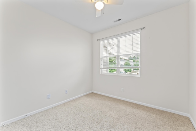 carpeted empty room with visible vents, a ceiling fan, and baseboards