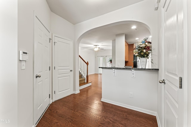 corridor with baseboards, stairway, recessed lighting, arched walkways, and dark wood-style floors