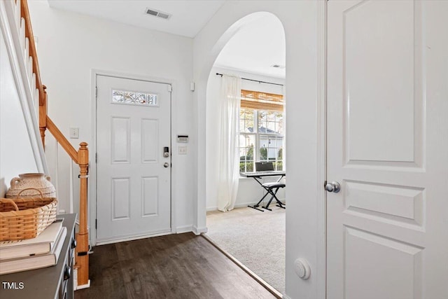 entryway featuring visible vents, arched walkways, baseboards, and dark wood-style floors