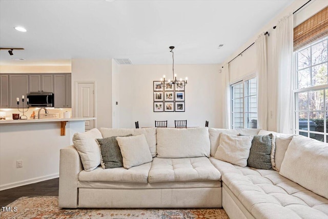 living room featuring baseboards, visible vents, recessed lighting, dark wood-type flooring, and a notable chandelier