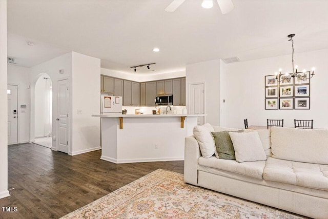 living room featuring baseboards, arched walkways, dark wood-type flooring, and ceiling fan with notable chandelier