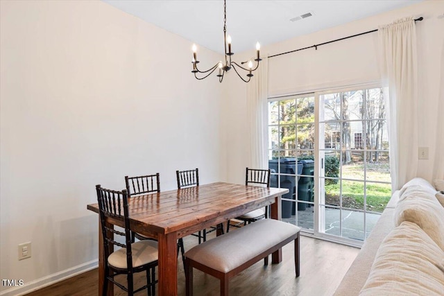 dining area with a notable chandelier, baseboards, visible vents, and wood finished floors