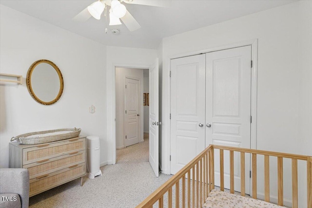 bedroom featuring baseboards, ceiling fan, a nursery area, a closet, and light colored carpet