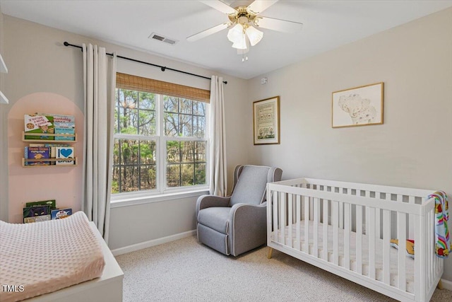 bedroom featuring a ceiling fan, baseboards, visible vents, a crib, and carpet flooring