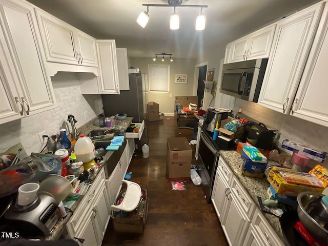 kitchen featuring light stone countertops, dark wood-style floors, appliances with stainless steel finishes, white cabinetry, and backsplash