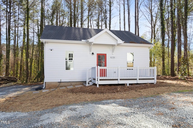 view of front of property with a deck and roof with shingles