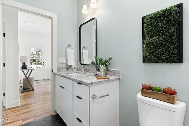 half bathroom featuring vanity, toilet, and wood finished floors