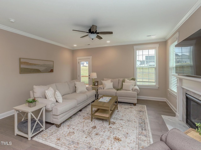 living area featuring crown molding, plenty of natural light, a ceiling fan, and baseboards