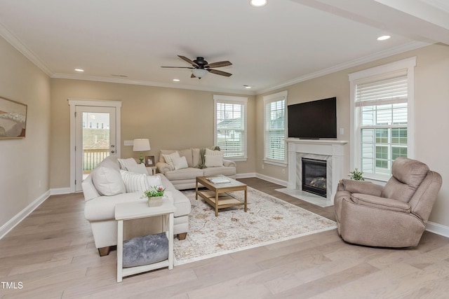 living room with plenty of natural light, wood finished floors, a ceiling fan, and ornamental molding