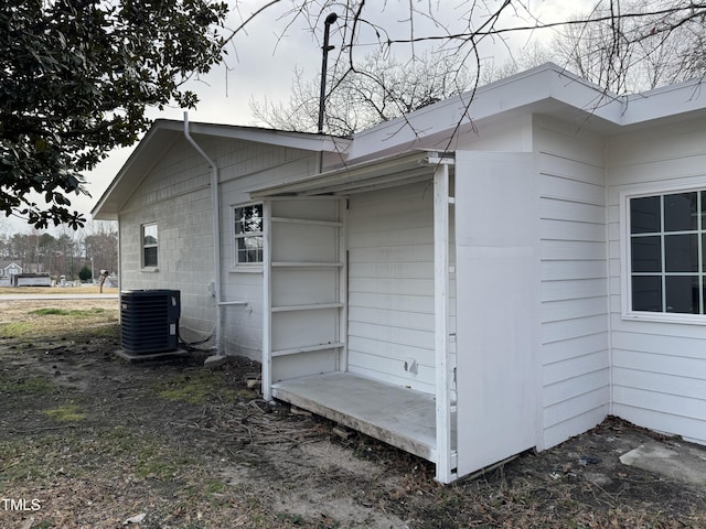 view of side of property with concrete block siding and cooling unit