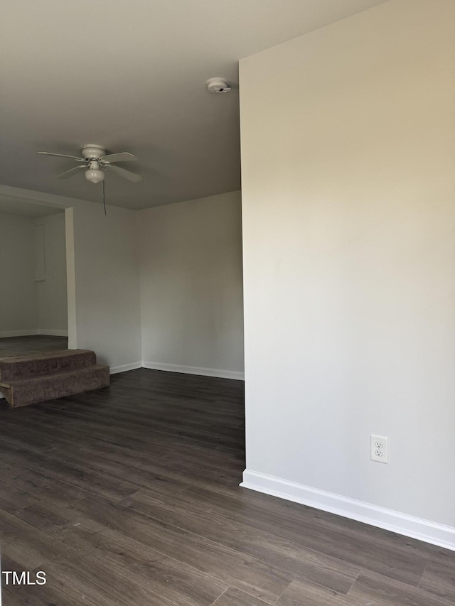 empty room featuring dark wood-style floors, a ceiling fan, and baseboards