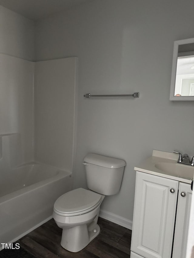 bathroom featuring toilet, wood finished floors, vanity, baseboards, and shower / bathtub combination