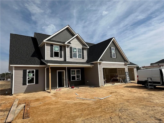 craftsman inspired home with a garage and roof with shingles