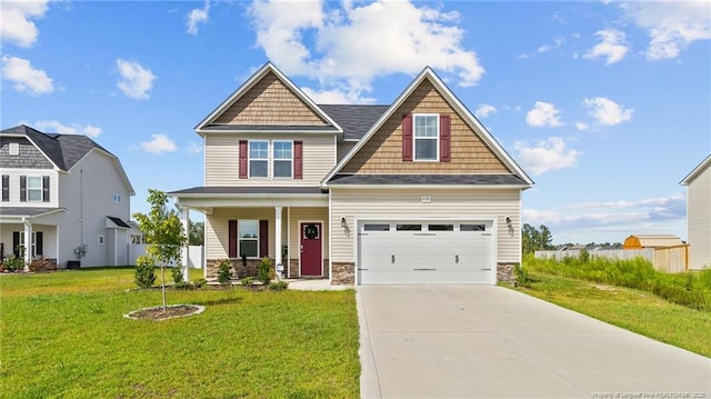 craftsman inspired home featuring concrete driveway, a front yard, covered porch, a garage, and stone siding